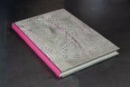 Cahier à couverture cuir gris clair, motifs ondulés, dos fuchsia en cuir.