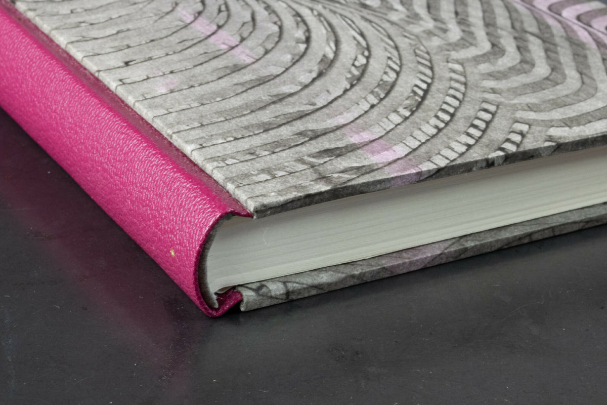 Reliure en cuir fuchsia et tranche du cahier, motifs ondulés sur la couverture.