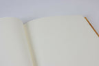 Carnet ouvert : pages blanches lisses, aperçu de la reliure et du bord