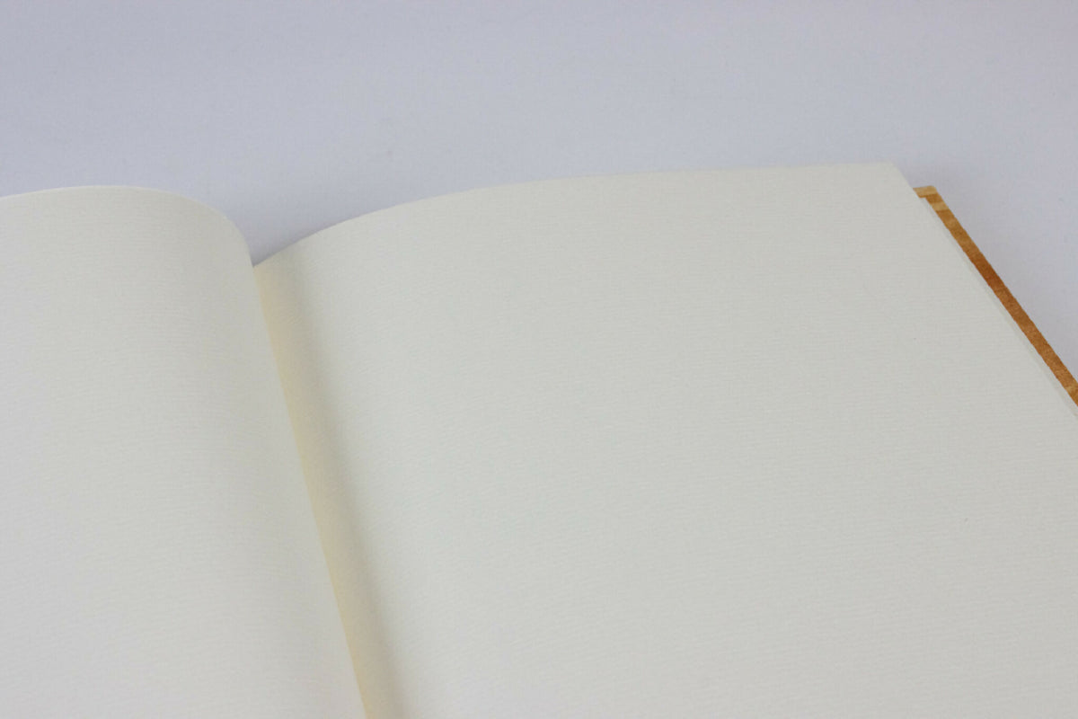 Carnet ouvert : pages blanches lisses, aperçu de la reliure et du bord