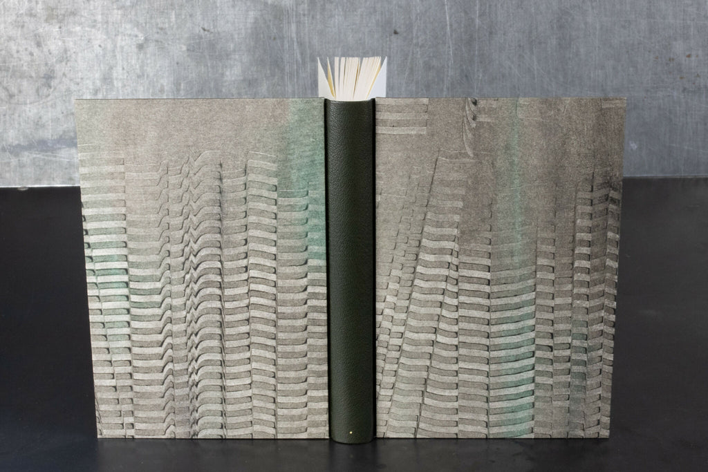 Carnet ouvert à couverture en cuir gris, motifs ondulés sur les pages