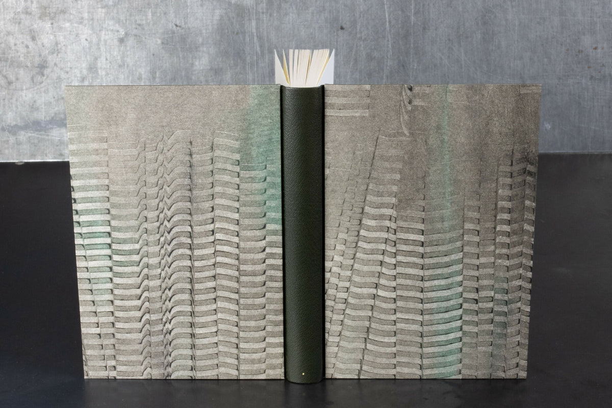 Carnet ouvert à couverture en cuir gris, motifs ondulés sur les pages