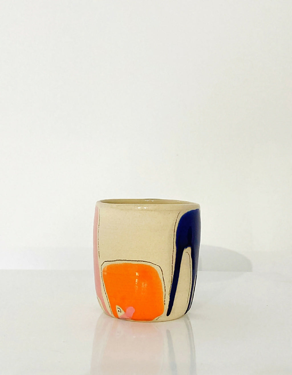 Gobelet en céramique beige avec motifs orange et bleu foncé