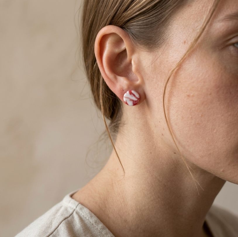 Clous d’oreille en porcelaine motif marbré rouge, portés sur l’oreille