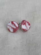 Clous d’oreilles en porcelaine, disques marbrés blanc et rouge, avec tige métallique.