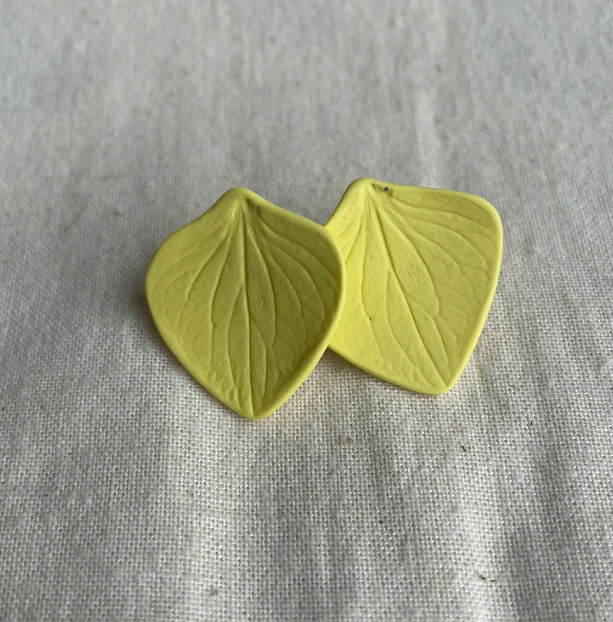 Boucles d’oreilles en porcelaine, deux pastilles en forme de feuilles jaune.