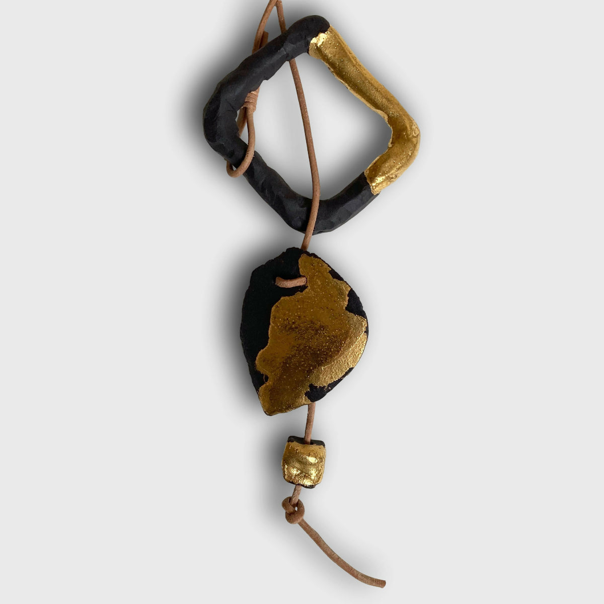 Collier à pendentif noir et doré en forme irrégulière, cordons marron