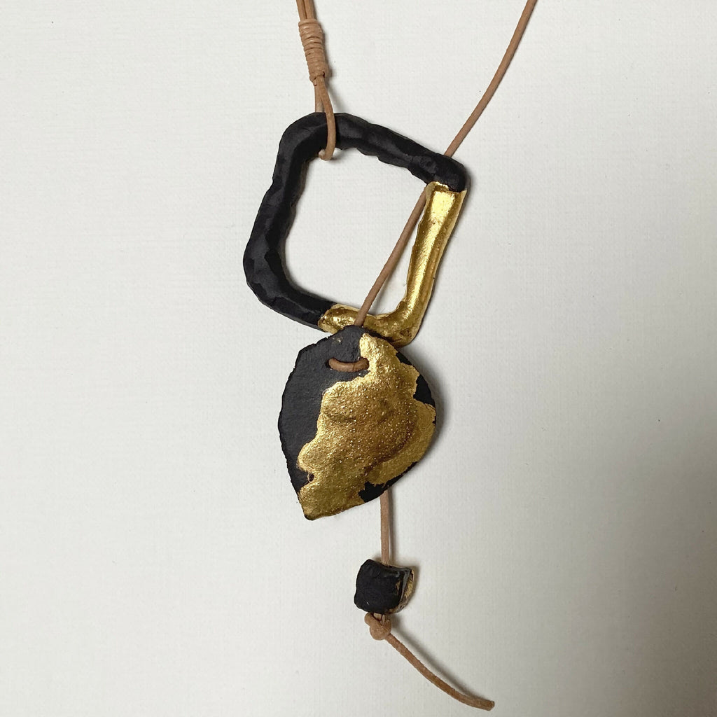 Collier avec pendentif noir et doré, monture carrée dorée visible