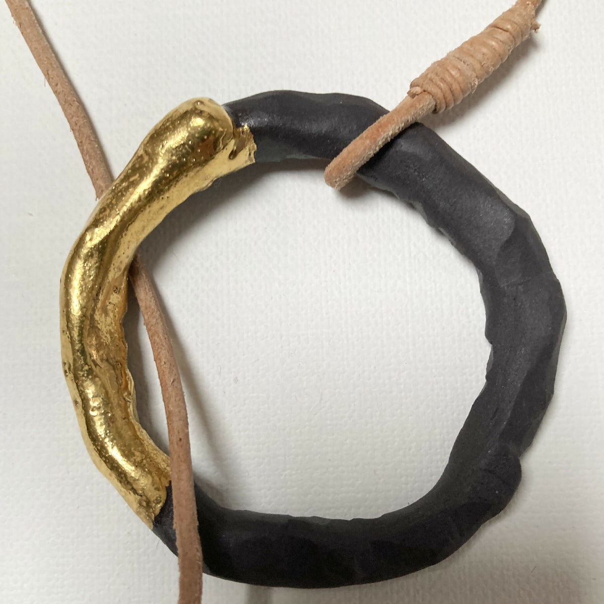 Collier anneau noir texturé et boucle dorée, cordon beige