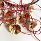 Collier aux fleurs dorées texturées et fils rouges, vue rapprochée