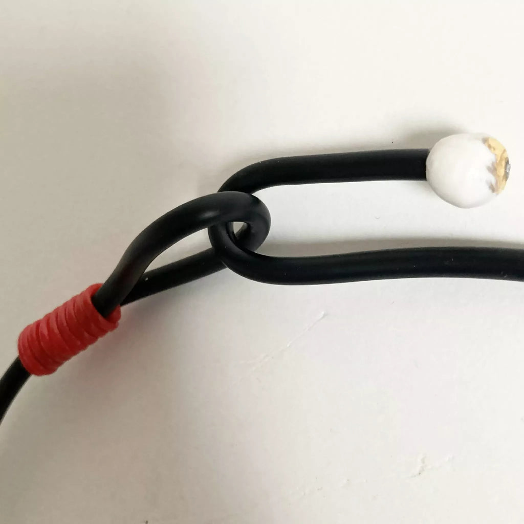 Fermoir du collier : cordon noir avec perle blanche et embout rouge