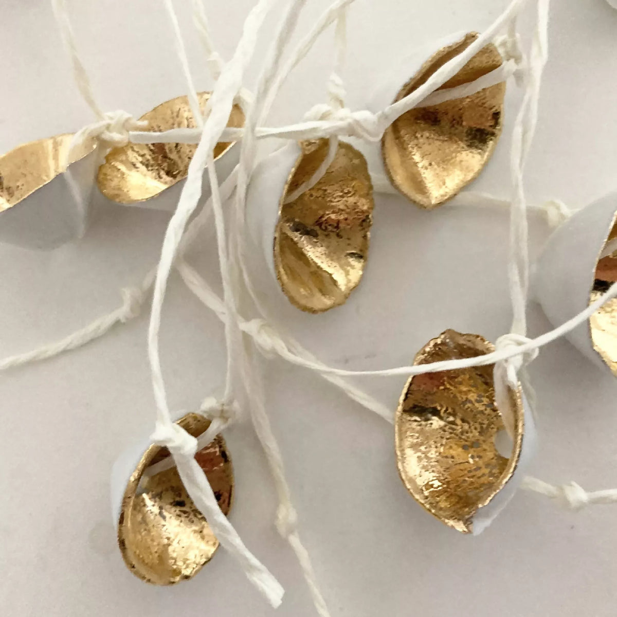Collier : breloques dorées martelées suspendues sur fils blancs, avec cordon noir