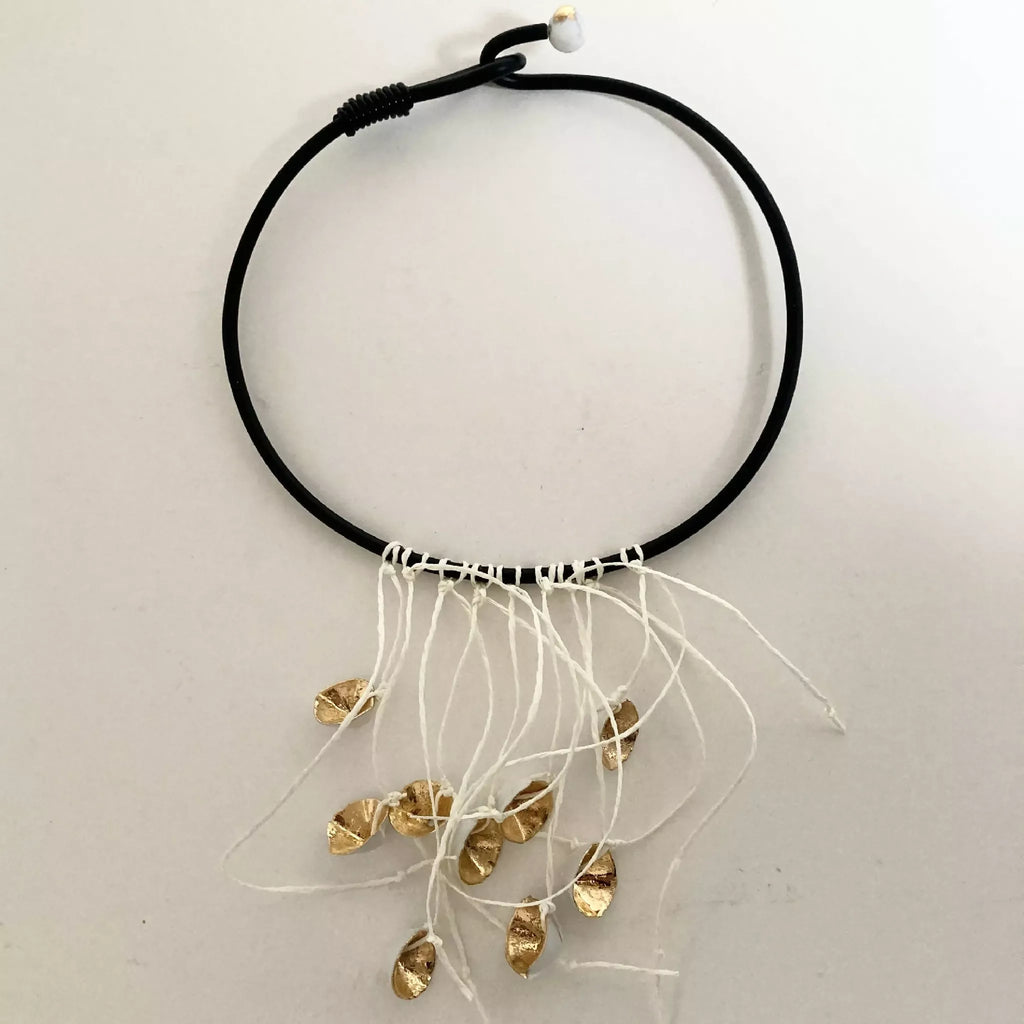 Collier à cordon noir avec franges blanches et plusieurs breloques dorées, vue de face