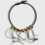 Collier noir en cordon avec disques dorés percés et petits fils noirs pendants