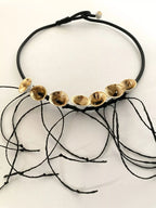 Collier en cordon noir avec plusieurs disques dorés et fils noirs décoratifs
