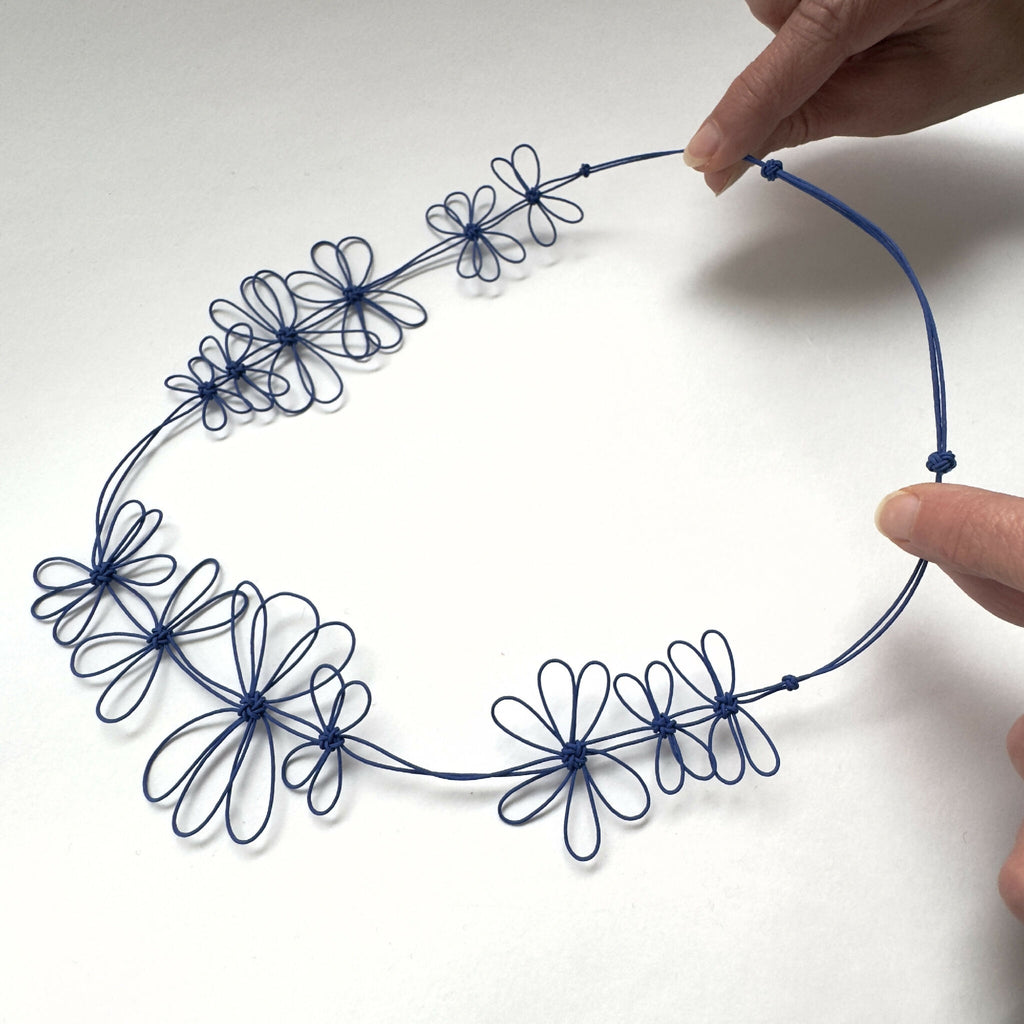 Collier de fleurs de prunier bleu, brins flexibles formant plusieurs fleurs en cercle.
