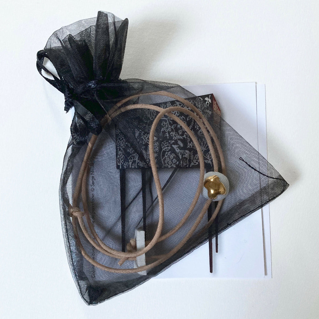 Collier en porcelaine dans un sachet en organza noir, pendentif goutte dorée.