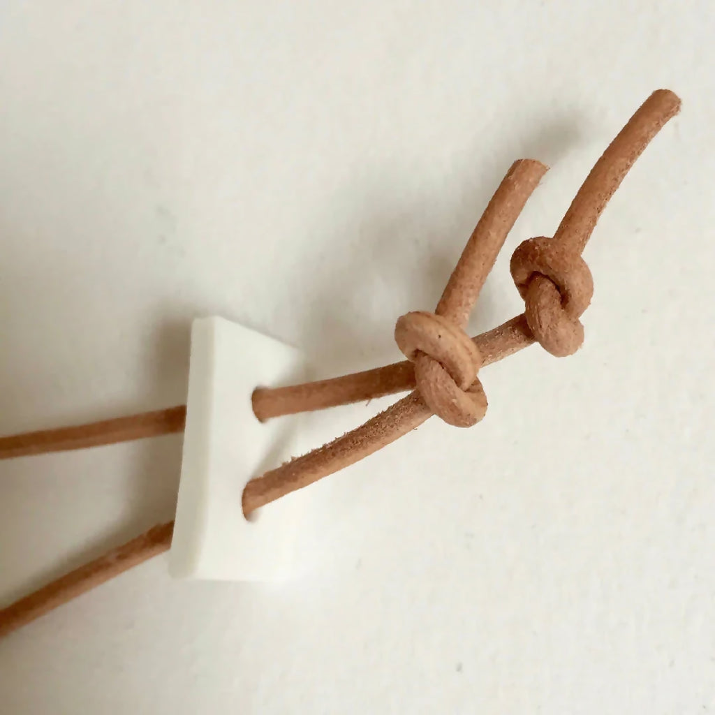 Collier : cordon en cuir brun avec nœud de fermeture, finitions beige