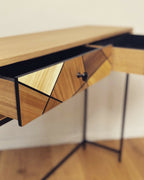 Détail de console en chêne : tiroir à losanges et bouton noir, structure noire