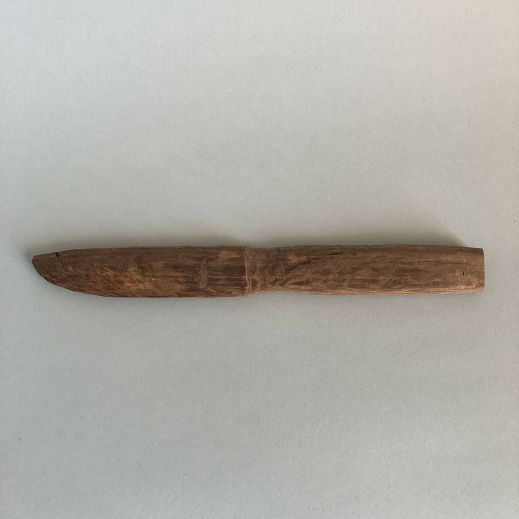 Couteau en bois taillé, lame effilée et manche intégré, brun, vue de profil.
