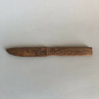 Couteau en bois taillé, lame effilée et manche intégré, brun, vue de profil.