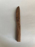 Couteau en bois taillé, manche et lame étroits, brun foncé, vue de côté.