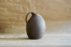 Cruche en céramique sombre, anse courbée, forme arrondie