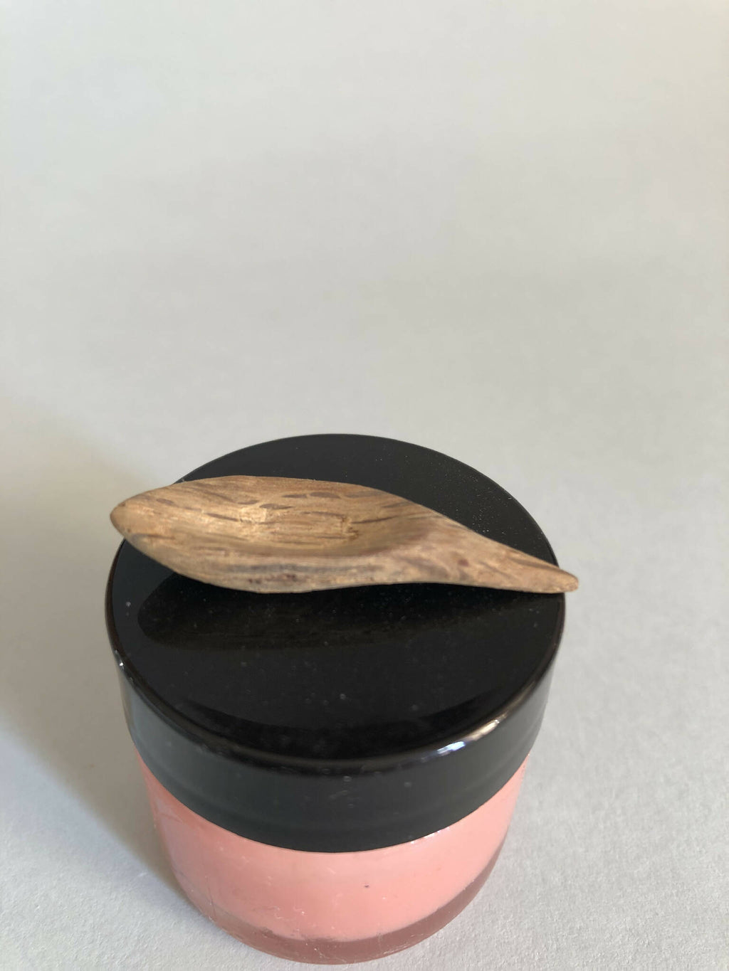 Cuillère à cosmétiques en bois posée sur couvercle noir