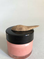 Cuillère à cosmétiques en bois sur pot rose à couvercle noir