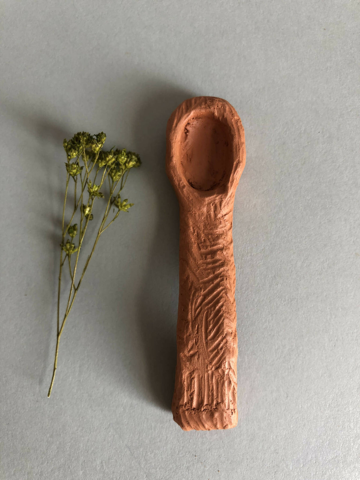Cuillère à thé en bois cuivré, bol ovale et manche texturé.