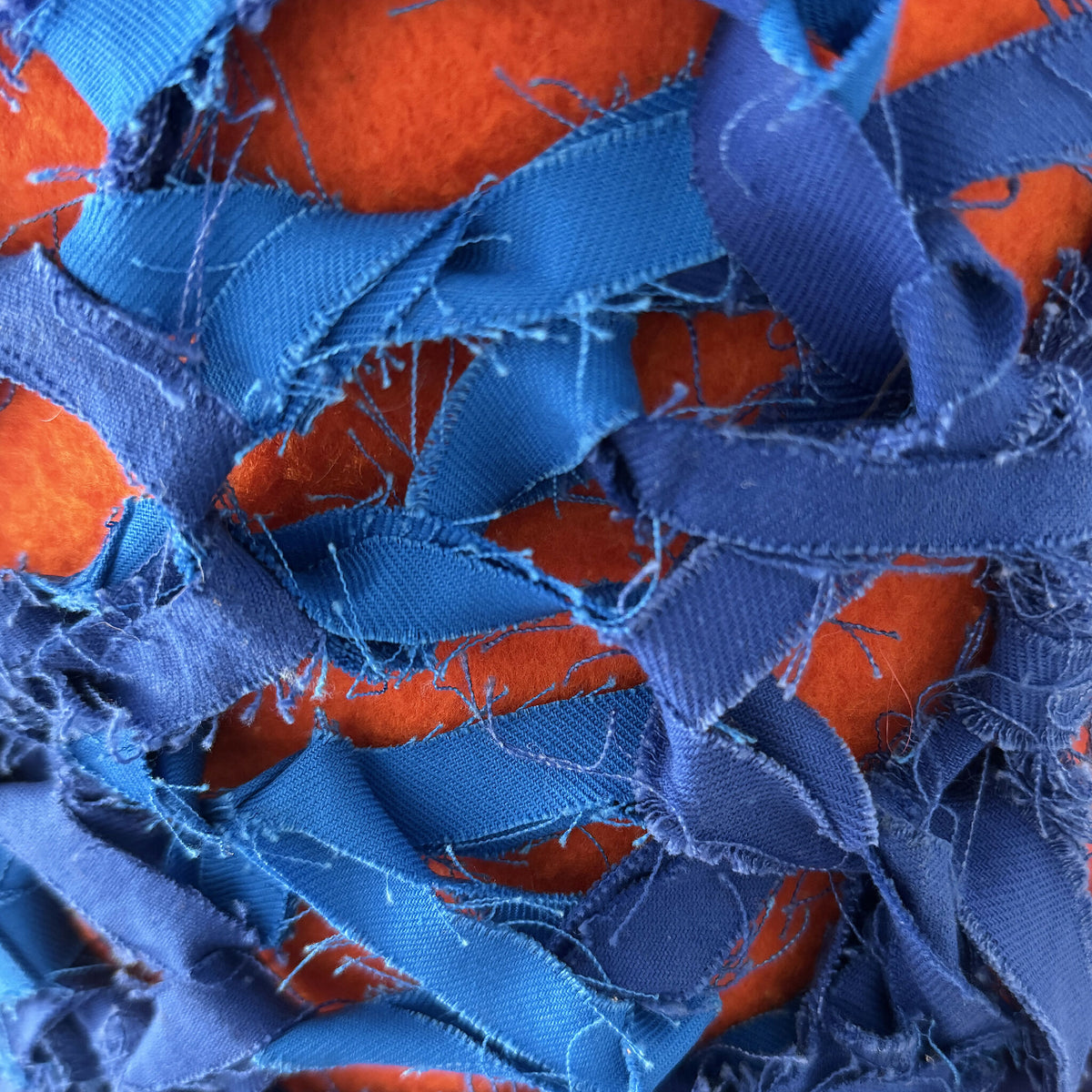 Cocoon décoratif bleu, gros plan sur tissage frangé avec touches orange