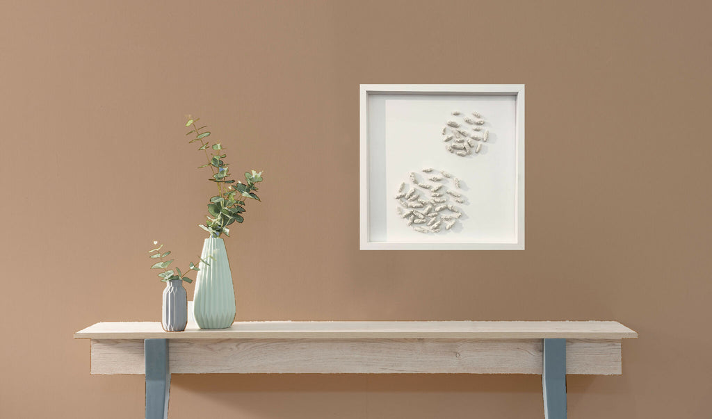 Petit tableau encadré en relief, motifs blancs, au-dessus d’une console