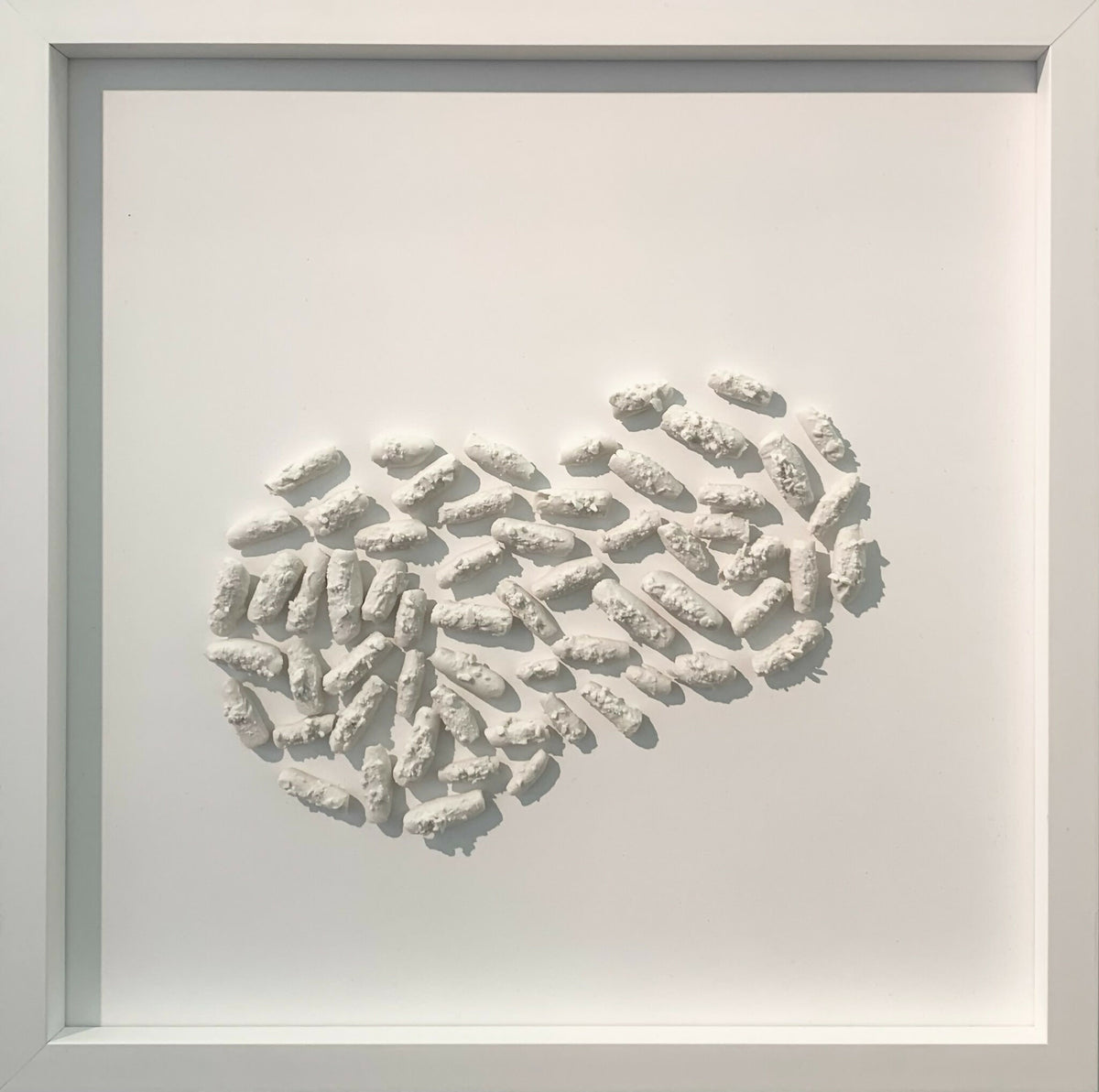 Tableau encadré en relief avec motif ondulé en éléments blancs, vue rapprochée