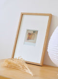 Cadre photo en bois clair avec passe-partout blanc et photo style Polaroïd