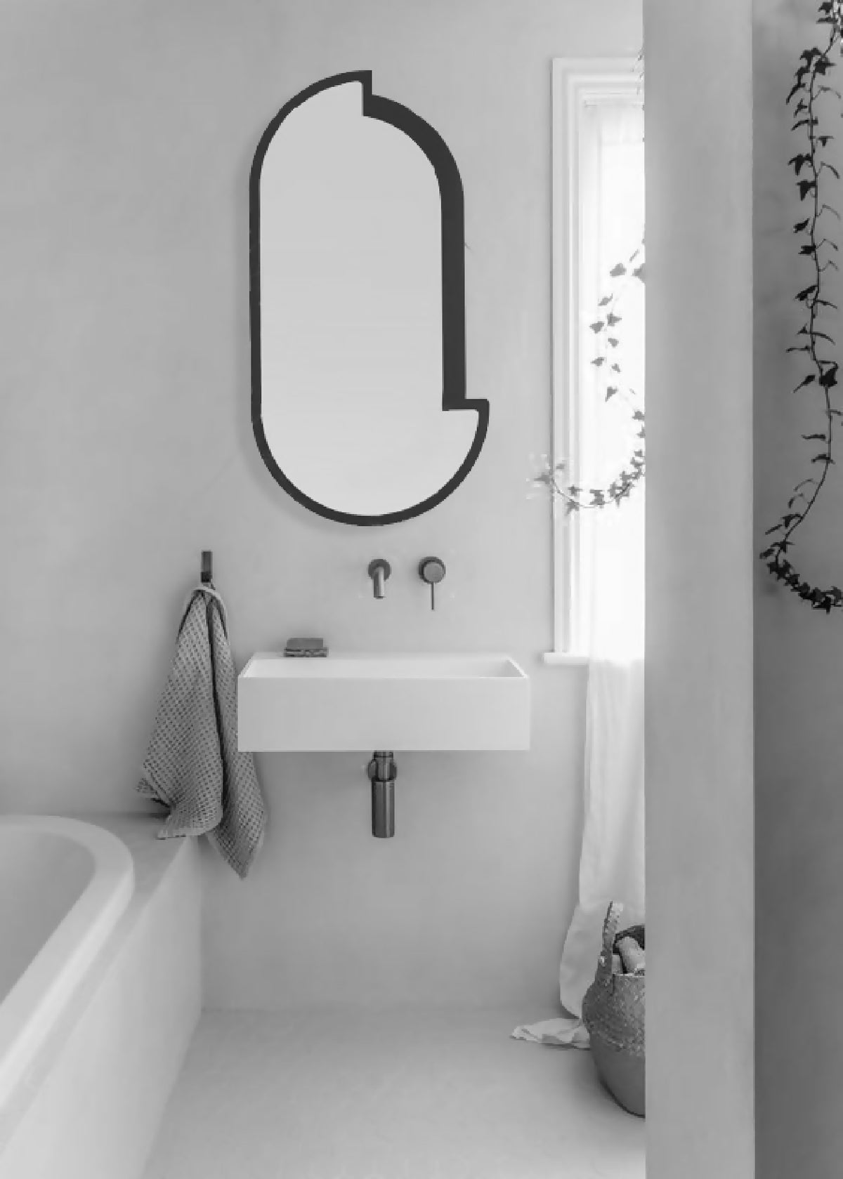 Miroir mural ovale à cadre noir, forme arrondie, style minimaliste.