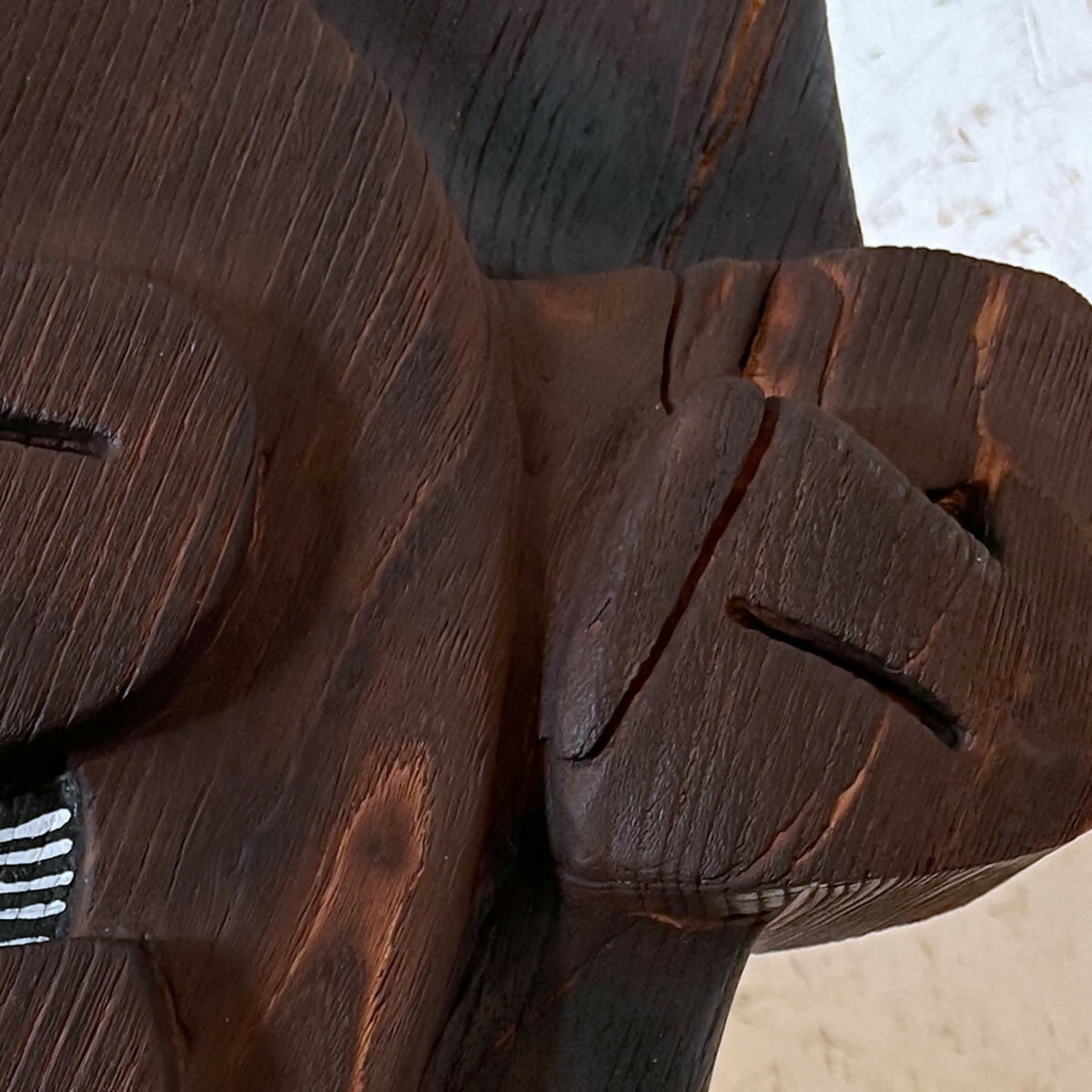Détail de la sculpture en bois foncé avec relief et lignes gravées