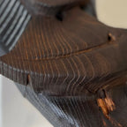 Gros plan : sculpture en bois sombre avec nervures et petites marques