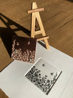 Tableau fleuri à cadre foncé et petite carte blanche, fleurs noires et papillons