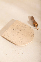 Dessous de plat LIO beige clair à taches, bord arrondi, texture granuleuse