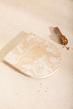 Dessous de plat LIO en pierre beige clair, bord arrondi, aspect granuleux avec taches