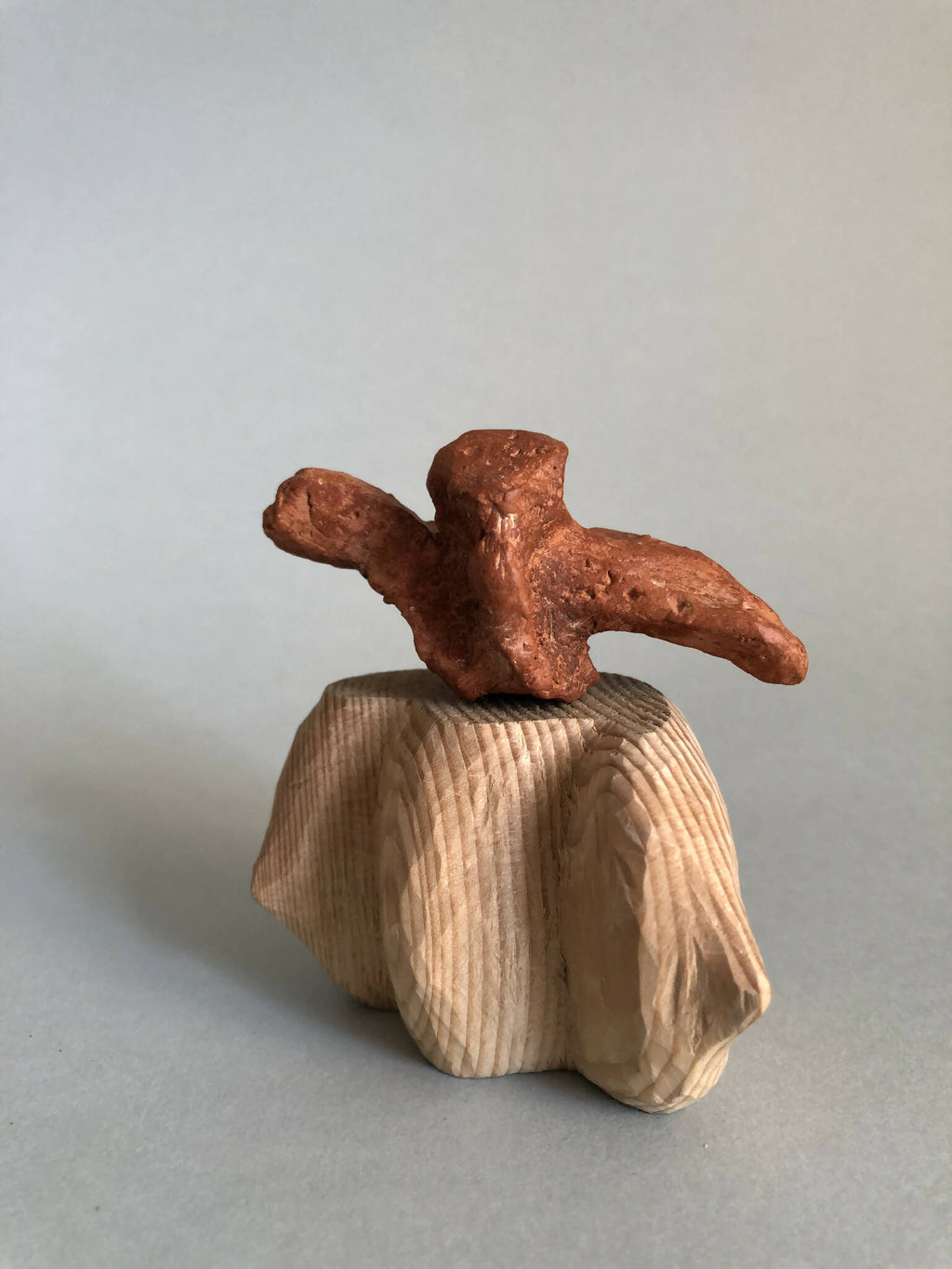 Petite sculpture en métal cuivré sur tissu plissé beige, vue de profil