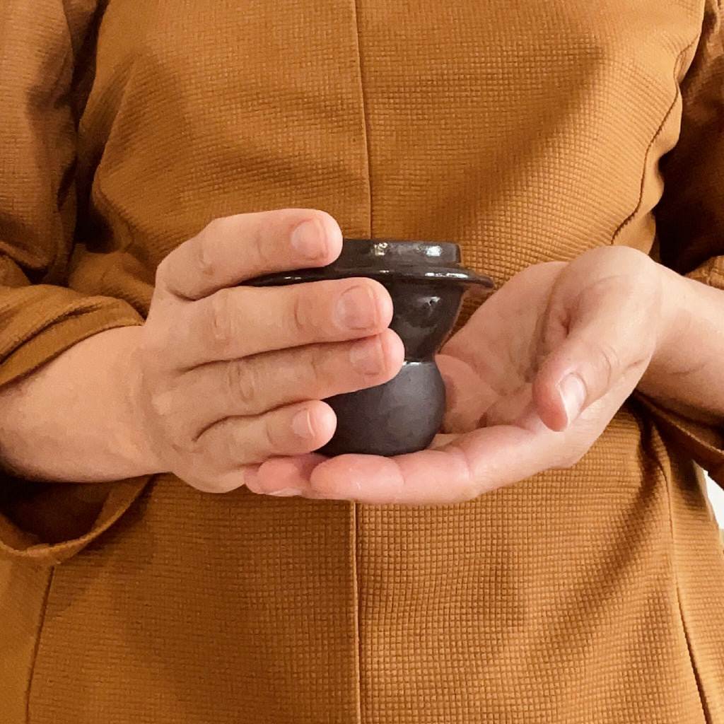 Duo de tasses à café en céramique sombre, tenu à deux mains