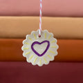 Pendentif en céramique jaune en rosace, cœur violet au centre et ruban rouge