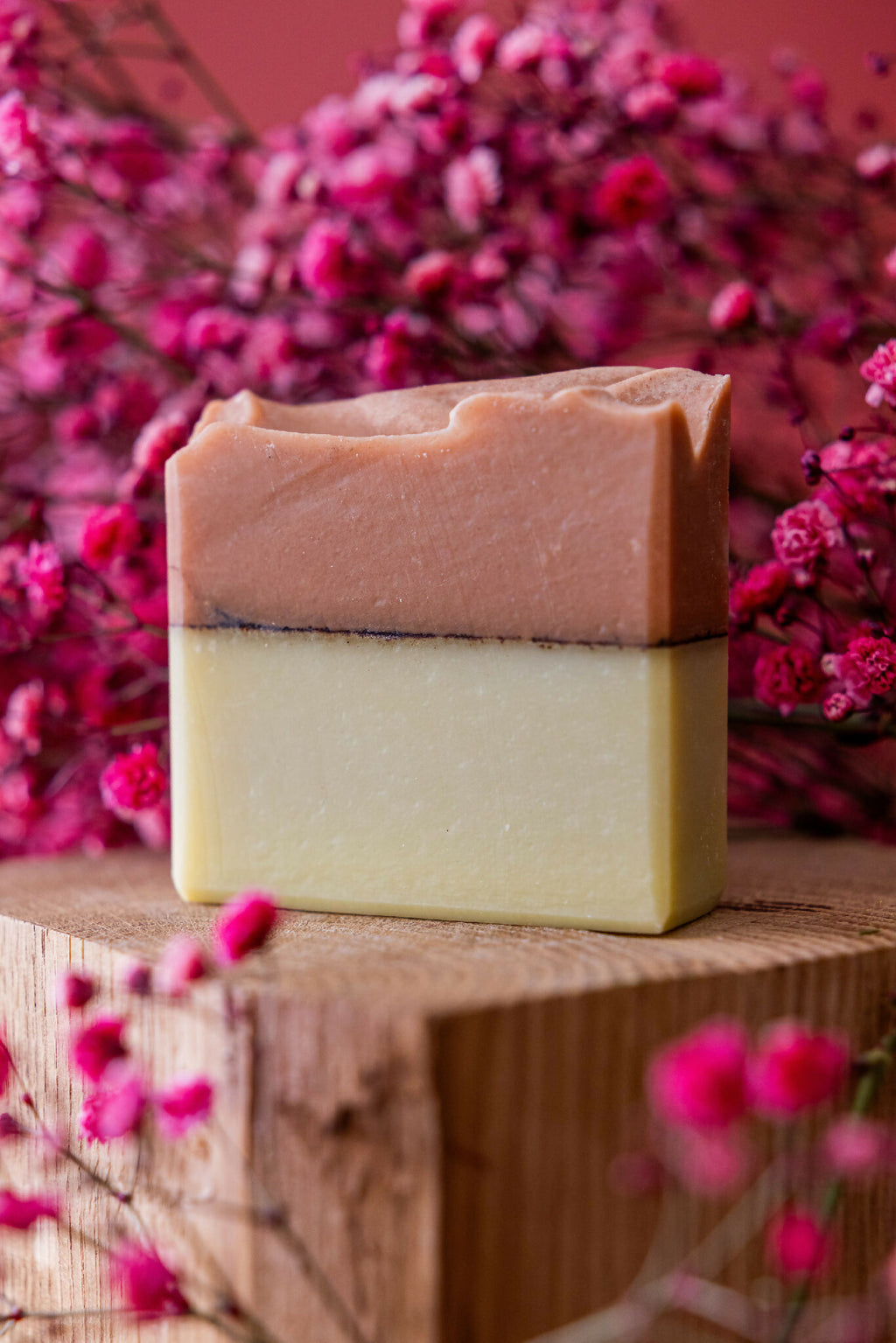 Savon en barre bicolore argile rouge et curcuma, tranche visible sur plateau en bois.