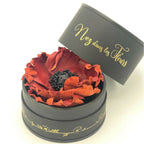 Bougie cylindrique noire « Nez dans les Fleurs », couvercle ouvert, fleurs rouges.