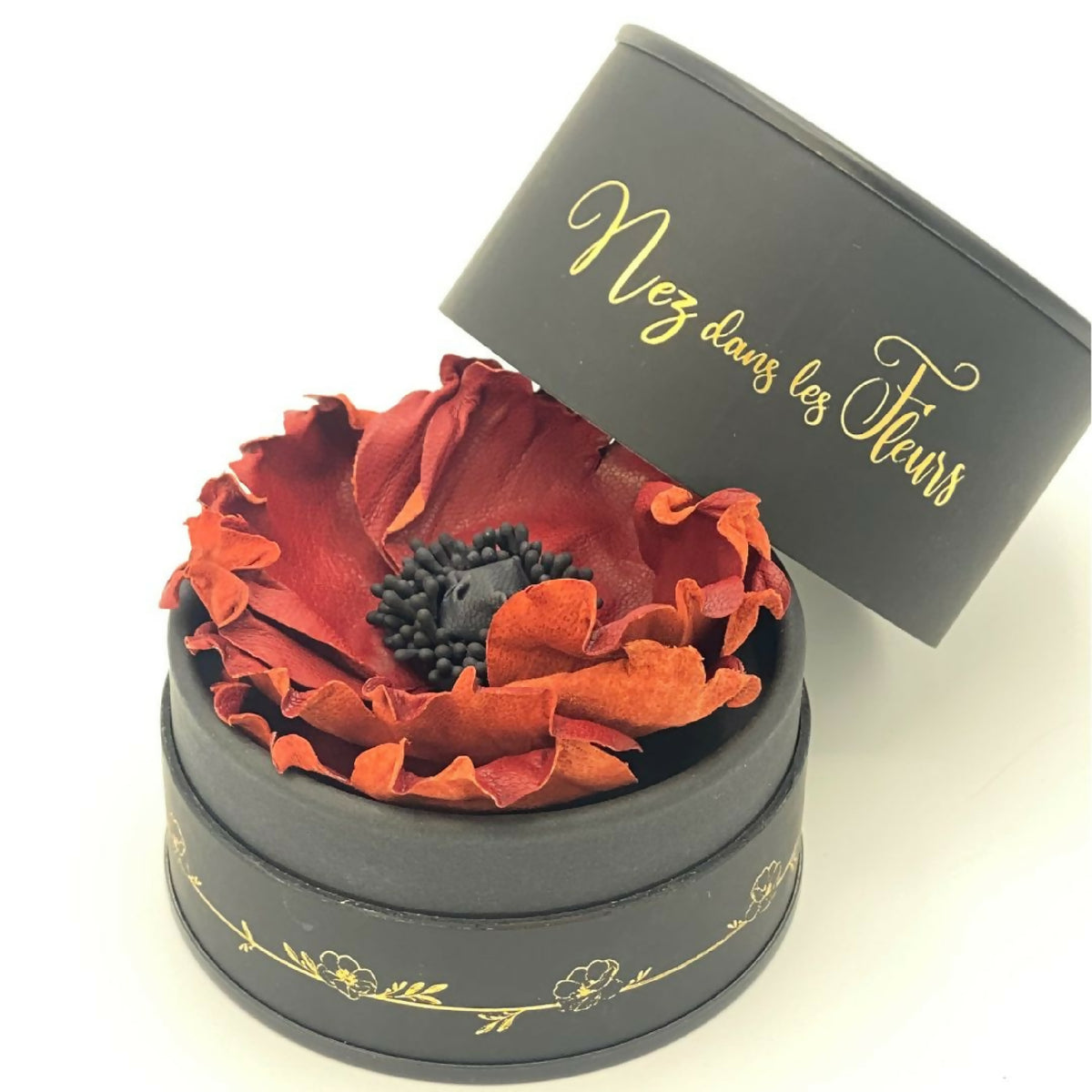 Bougie cylindrique noire « Nez dans les Fleurs », couvercle ouvert, fleurs rouges.