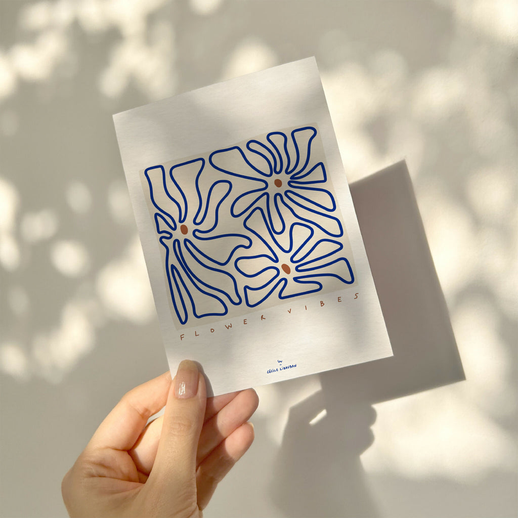 Carte illustrée fleurs abstraites bleues, tenue dans une main.