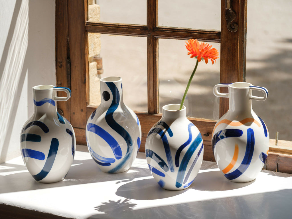 Ensemble de vases bustes en céramique blanche, anses, motifs bleu/orange abstraits.