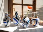 Ensemble de vases bustes en céramique blanche, anses, motifs bleu/orange abstraits.