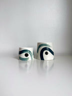 Deux grandes tasses trapèze en céramique blanche, motifs vert et bleu.